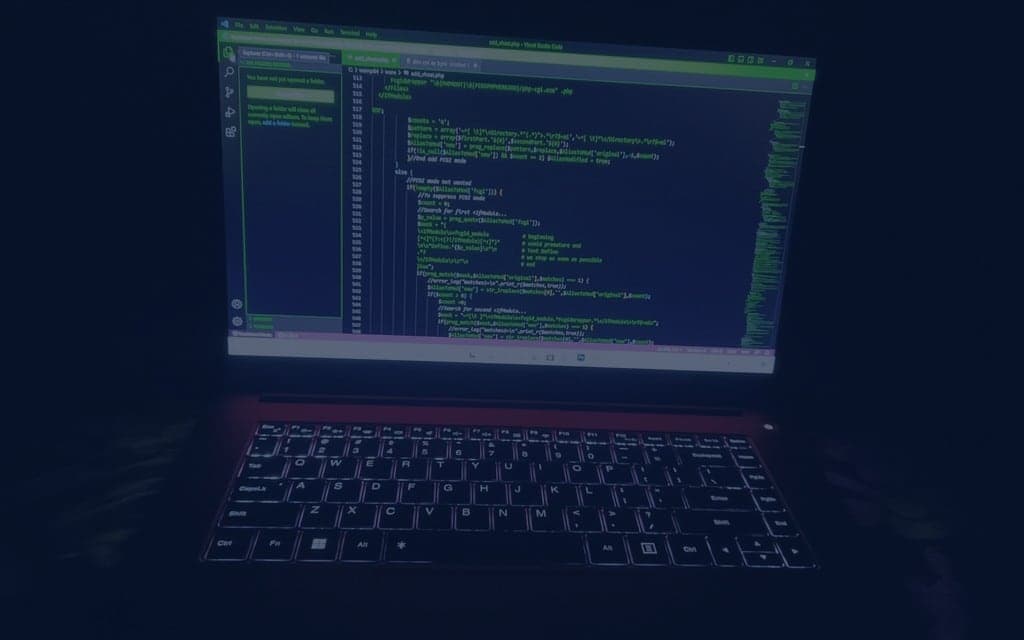 Laptop with illuminated keyboard and green text in dark room