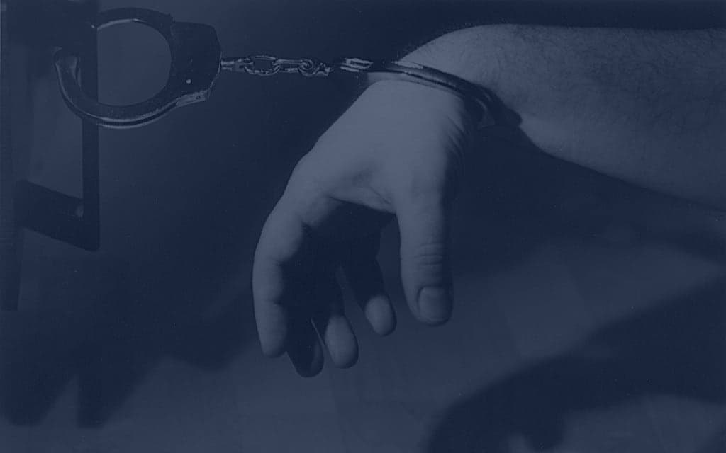 A pair of metal handcuffs on a plain background